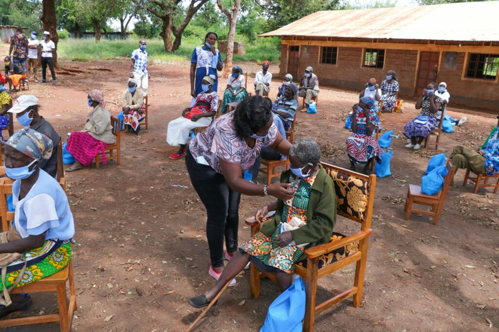 black elderly people sitting on chairs in yard of hospital in poor african village